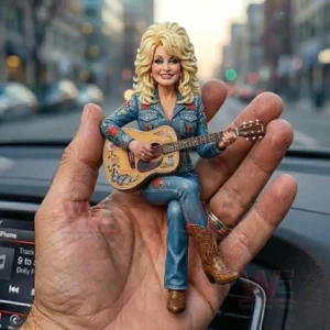 Small resin figure of a blonde country singer in embroidered denim holding a decorated acoustic guitar while sitting in a hand inside a car!
