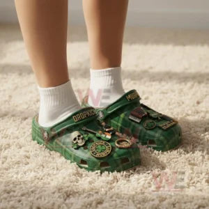 Person wearing green plaid clogs with white socks featuring dropkick murphys strap lettering and Irish themed music charms.