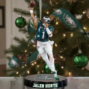 The image displays a Jalen Hurts ornament in a quarterback throwing pose standing on a base with his name placed before a Christmas tree decorated in green and white.