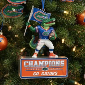 A Gators themed mascot ornament holding a flag and a ball hanging on a decorated Christmas tree!