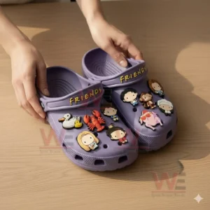 A pair of purple themed clogs shown on a table adorned with multiple charms referencing well known characters and symbols from the sitcom!