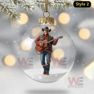 Christmas globe ornament with cowboy standing holding guitar and wrapped in festive lights!