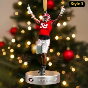 A Christen Miller ornament showing him celebrating with raised arms above a nameplate in front of a Christmas tree!