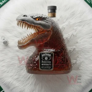 A creature shaped whiskey bottle featuring an open mouth and textured body positioned on a fluffy white surface.