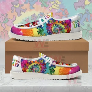 Rainbow tie dye canvas shoes with dancing bear prints and Grateful Dead heel text displayed on and in front of a brown shoebox with a colorful patterned background.
