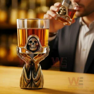 Whiskey glass held by a grim reaper themed stand with a man drinking behind it!