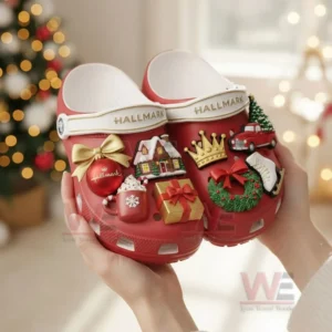 Red Hallmark themed clogs with Christmas charms held in front of a glowing tree!
