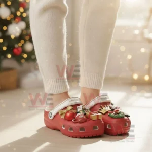 A person wearing red Hallmark themed clogs with Christmas charms in a festive room!
