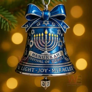 Blue Hanukkah bell ornament with menorah and festive symbols hanging on a tree branch with glowing lights behind!