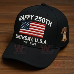 A close view of a black anniversary cap showing an embroidered American flag celebratory text and a liberty bell emblem against a wooden surface!