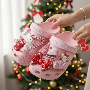 Pink Hello Kitty clog shoes with Christmas charms displayed in front of a decorated tree!