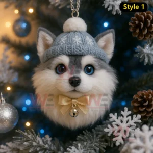 A fluffy puppy ornament with mismatched eyes wearing a blue knitted hat and gold bow hanging on a snowy Christmas tree!