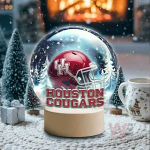 A snow globe with a red team helmet sits in a snowy room with a glowing fireplace and holiday decor!