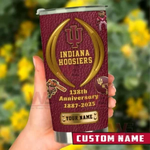 Hand holding an Indiana Hoosiers custom name tumbler in maroon and gold featuring 138th anniversary 1887 to 2025 text and team themed icons against a blurred garden background!