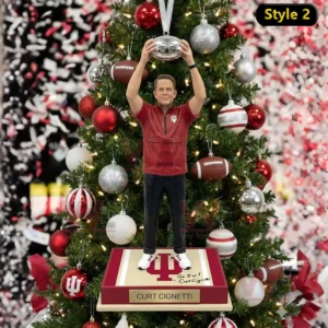A Curt Cignetti ornament showing him lifting a silver ball above a nameplate base before a festive Christmas tree!