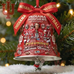 A red bell ornament on a Christmas tree shows Indiana Hoosiers players coach and the Big Ten trophy with a small bulldog figure hanging underneath!
