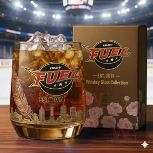 A close view of an Indy Fuel whiskey glass filled with an amber drink and ice displayed beside its gold floral decorated box with city skyline engravings!