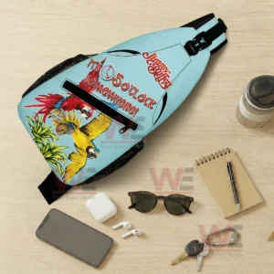 Jimmy Buffett Personalized Sling Bags 5 Light blue parrot sling bag displayed flat with everyday items including phone sunglasses keys and notebook on a wooden surface!