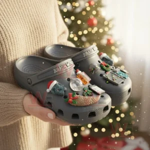 Jurassic World Christmas Crocs Clogs with Charms 5 Gray Jurassic World Christmas clogs with dinosaur charms held near a Christmas tree!