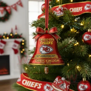 A red Chiefs anniversary bell ornament hanging on a Christmas tree with festive decorations in the background!