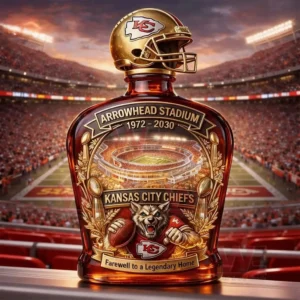 Brown decanter style bottle with a gold KC football helmet topper and an Arrowhead Stadium farewell label shown in front of a crowded stadium at sunset.