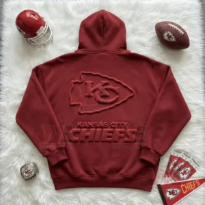 Flat lay of a red Kansas City Chiefs hoodie with raised logo surrounded by football accessories!