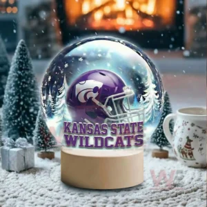 A snow globe with a purple team helmet sits in a snowy room with a glowing fireplace and holiday decor!