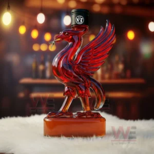 Red glass bird bottle with wings raised standing on a soft white surface with warm bar background!