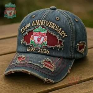 A close view of a blue denim cap with torn fabric accents and an embroidered football club badge resting outdoors on a wooden table!