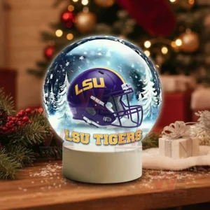 A snow globe with a purple team helmet sits on a wooden table surrounded by holiday decorations!