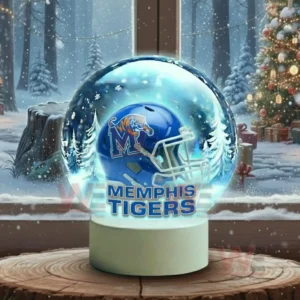 A snow globe with a blue team helmet sits on a wooden surface with snowy trees visible outside the window!