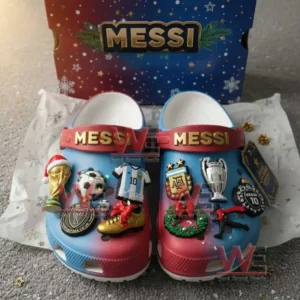 A close view of blue and red Messi themed clogs covered in football and holiday charms displayed in front of a Messi box!