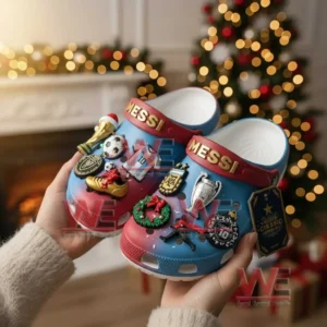 Hands holding Messi decorated clogs in front of a Christmas tree full of warm holiday lights!