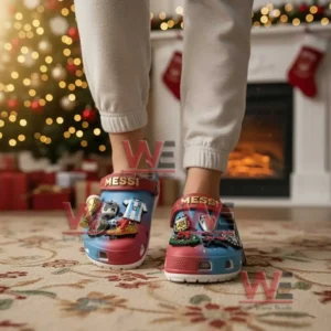 Feet wearing Messi themed clogs covered in football and Christmas charms with a decorated Christmas tree behind them!