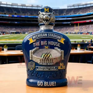Michigan Stadium themed collector whiskey bottle with animal head stopper stadium illustration and bold blue design shown in a football stadium!