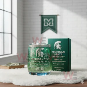 Michigan State University anniversary glass with green iced drink beside a dark green box displaying the Spartan emblem and historical information!