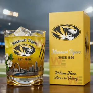 Missouri Tigers themed drink glass with ice and golden beverage next to a yellow branded box on a table with stadium lights in the background!