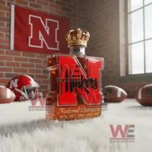 A red N shaped Huskers bottle standing on a fluffy surface with football items and team banners behind it!