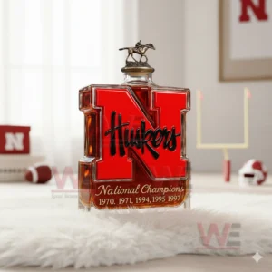 A red N Huskers bottle standing on a fluffy surface with sports items and decor elements behind it!
