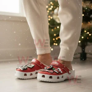 Feet wearing red New Kids On The Block clogs decorated with music and Christmas themed charms in a festive indoor setting.