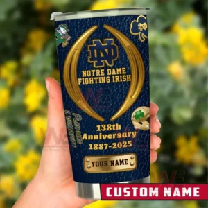 Hand holding a Notre Dame Fighting Irish custom name tumbler in navy and gold featuring 138th anniversary 1887 to 2025 text and team themed icons against a blurred garden background!