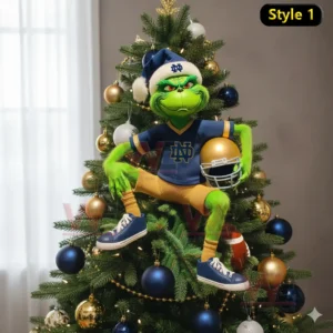 A green figure in a blue outfit holding a football helmet sits on the branches of a decorated Christmas tree.