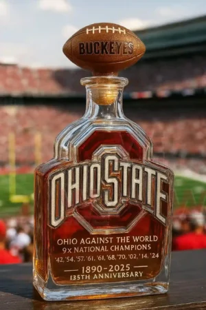 Ohio State Buckeyes themed liquor bottle with football topper and engraved front design placed on a table with a football stadium in the background!