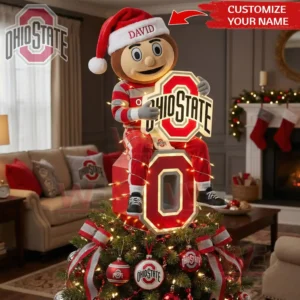 An Ohio State mascot in a Santa hat sitting on a glowing emblem atop a decorated Christmas tree in a festive room!