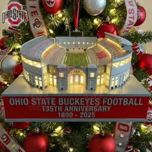 A miniature Ohio State Buckeyes football stadium ornament glowing with lights and hanging on a Christmas tree surrounded by red silver and white decorations!