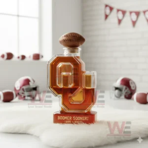 An OU shaped Sooners bottle with a football cap placed on white fur with helmets and banners behind it.