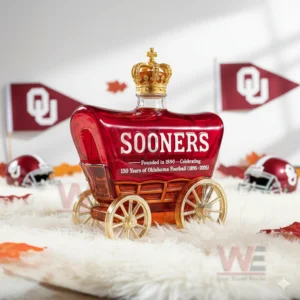 A wagon shaped Sooners bottle rests on a fluffy white rug with team flags helmets and seasonal leaves arranged around it!