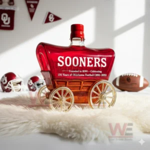Oklahoma Sooners 130 Years Of Oklahoma Football Whiskey Bottle 5 A Sooners wagon bottle rests on a soft white rug surrounded by helmets footballs and red team banners!
