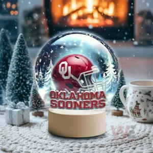 Holiday themed snow globe with Oklahoma Sooners helmet on a white base near fireplace and winter decorations!