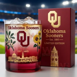 Oklahoma Sooners themed whiskey glass with amber drink ice cubes and decorative design next to a branded collector box!